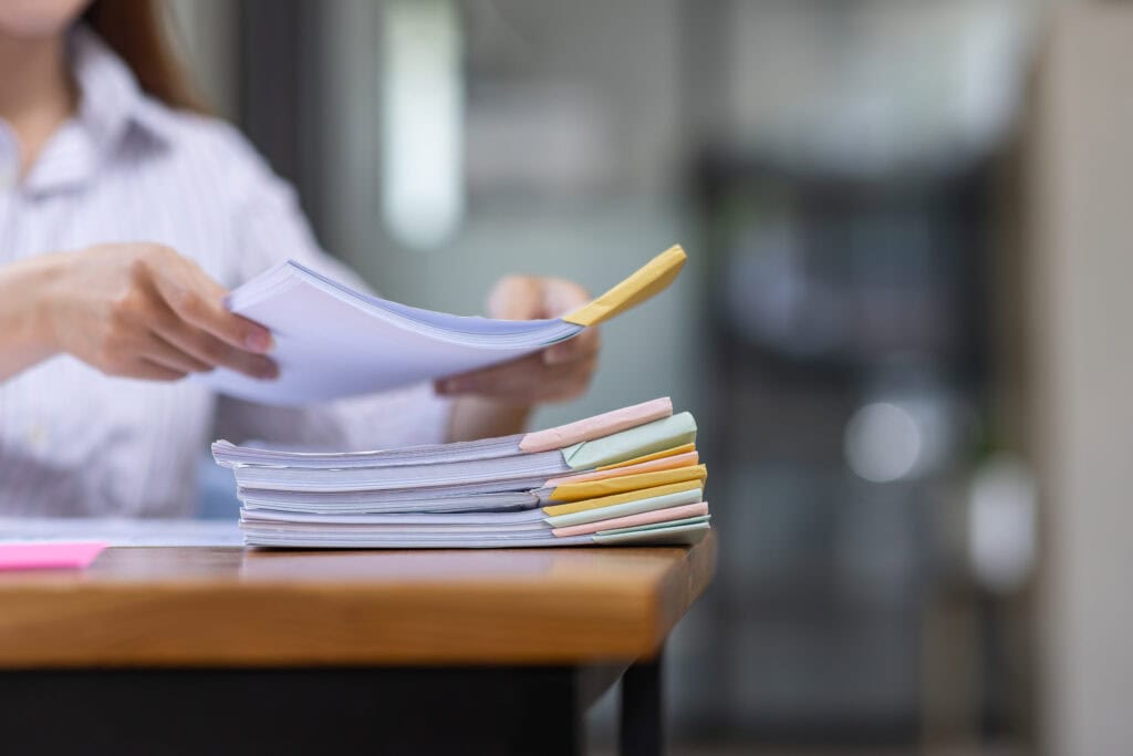 Person arranges colorful documents on desk.