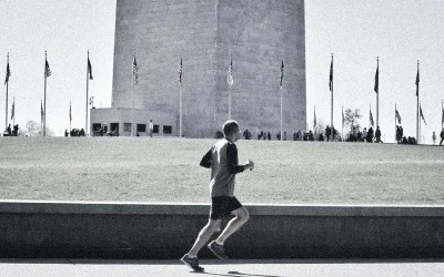 Läufer vor Monument mit Flaggen im Hintergrund